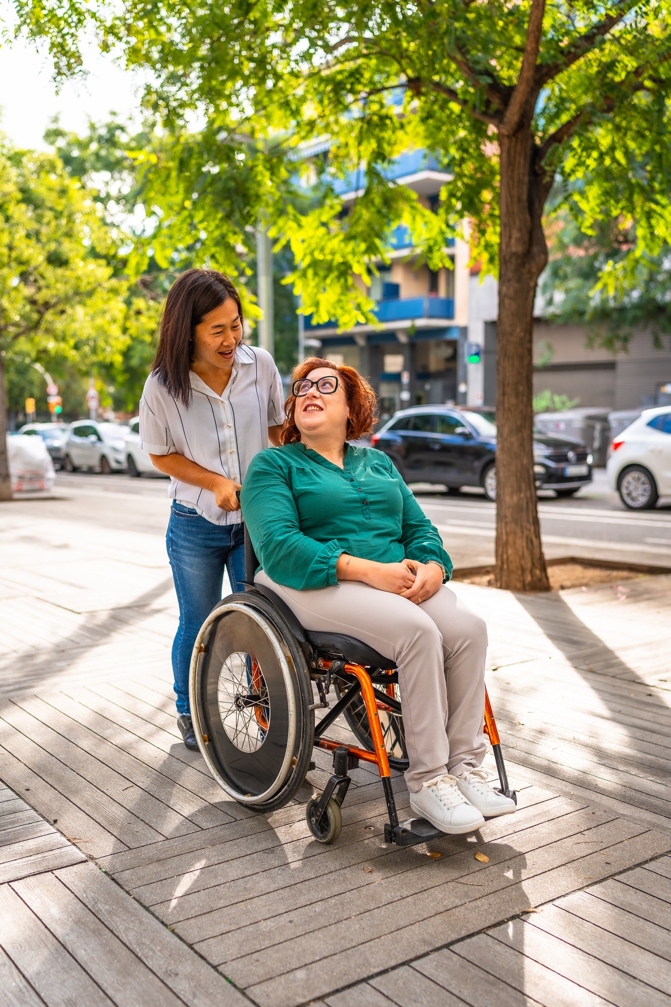 Asian caregiver pushing the wheelchair of a happy disabled woman